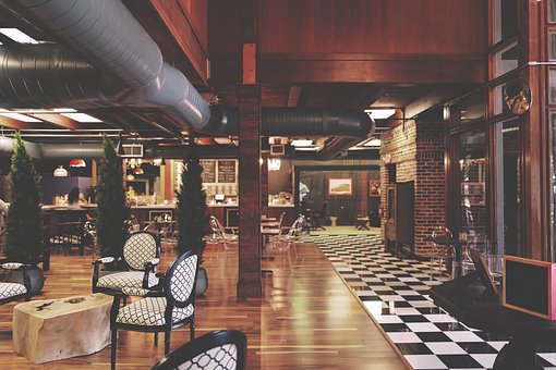 Interior of one of the most decadent hotel restaurants with dark wood furnishings and monochrome checker board floor.